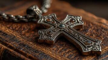 Intricate silver cross pendant resting on an antique book in soft light creating a serene and contemplative atmosphere photo