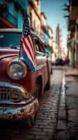 Classic car parked on a cobblestone street in Havana with an American flag during a sunny day photo