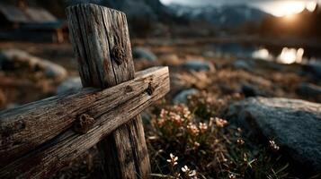Wooden cross standing among stones and flowers near a tranquil lake during sunset in a mountainous landscape photo