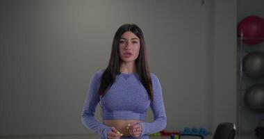 Sporty girl announcer presents fitness tips on camera in a well equipped gym during an afternoon broadcast video