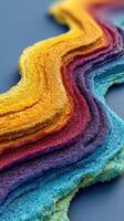 Colorful sand patterns create a vibrant and textured landscape on a blue surface during daylight photo