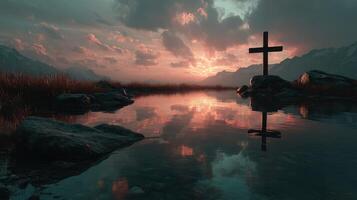 Sunset over tranquil water with a cross and mountains in the background at twilight photo