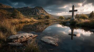 Reflection of a cross by a tranquil lake with mountains in the background during sunset photo