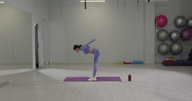 Girl performs a deep stretch in a fitness studio during a morning workout session for flexibility and strength video