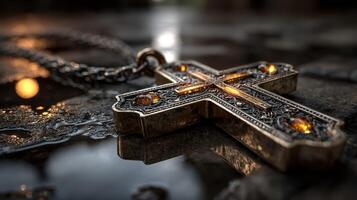 Intricate silver cross pendant with gemstones resting on a reflective surface showcasing detailed craftsmanship at sunset photo