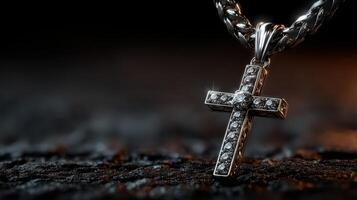 Silver cross necklace with intricate detailing resting on a textured surface illuminated by soft light photo