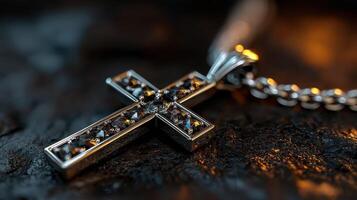 Silver cross necklace with sparkling gemstones displayed on textured surface during low light setting photo
