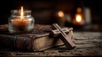 Candle and cross on a weathered book in a dimly lit setting creating a serene atmosphere photo