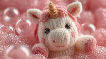 Cute knitted unicorn toy surrounded by pink bubbles in a playful setting photo