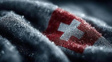 Detailed view of a Swiss flag stitched on textured fabric with water droplets reflecting light photo