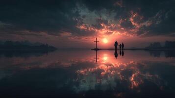 Couple walking at sunset near a cross by the water reflecting a vibrant sky photo