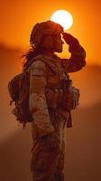 Soldier saluting at sunset in military uniform on a desert landscape during golden hour photo