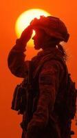 Silhouette of a soldier saluting at sunset during a military training exercise in a desert setting photo
