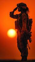 Soldier salutes at sunset with vibrant orange sky in the background representing honor and dedication photo