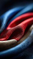 Close-up view of softly draped fabric in vibrant red, blue, and beige colors showcasing texture and sheen photo