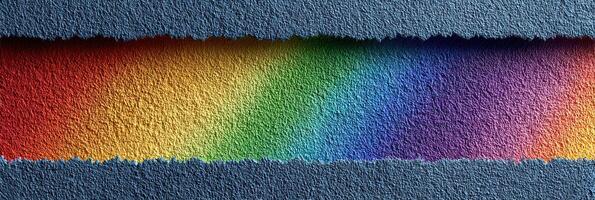 Colorful rainbow pattern on textured paper displayed against a blue background, showcasing vibrant hues and paper edges photo