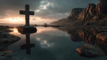 Cross silhouette at rocky shoreline during sunset near calm water reflects dark clouds and rugged cliffs photo