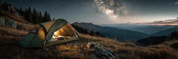 Camping beneath a starry sky in the mountains with a glowing tent at dusk photo