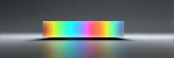 Colorful light spectrum reflecting off a transparent rectangular prism on a smooth gray surface photo