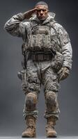Military soldier in tactical winter gear salutes while standing in a neutral setting during a cold day photo