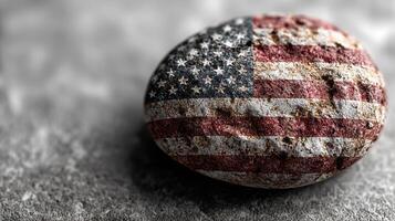 Unique rock painted with the American flag design displayed on textured surface in well-lit environment photo
