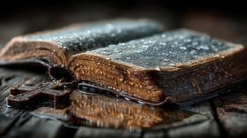 Old Bible with water droplets resting on wooden surface during rainy weather photo