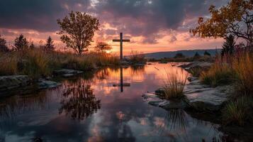 Serene sunset with a cross reflected in calm waters at a peaceful natural landscape photo