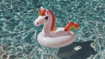 Colorful inflatable unicorn floating in a clear swimming pool under bright sunlight photo
