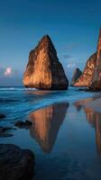 Dramatic rock formations reflected on the clear waters at a tranquil beach during golden hour in Bali photo