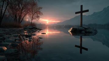Cross reflecting on tranquil lake at sunset near mountains and trees in a serene natural landscape photo