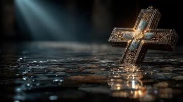 Cross illuminated in reflective water with soft light highlighting ornate details in a darkened environment photo