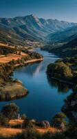 Scenic river meandering through lush valleys under a clear blue sky in the mountains at sunset photo