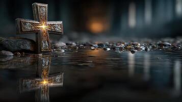 Reflective cross resting on stones beside a calm water surface in a dimly lit environment at twilight photo