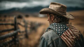 Cowboy wearing American flag scarf gazes toward distant mountains on a cloudy day in a rural landscape photo