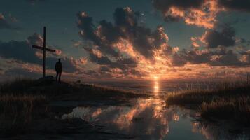 Sunset casts dramatic shadows over the ocean while a figure stands near a cross at the shore photo