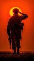 Soldier saluting against a striking sunset backdrop at a military base during late evening hours photo