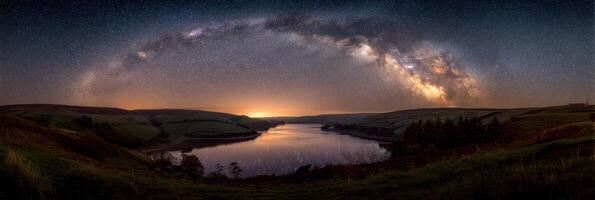 Stunning view of the Milky Way arching over a serene lake at dusk near rolling hills photo