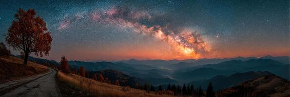 Night sky over rolling hills with a vibrant Milky Way and autumn trees near a winding road in the mountains photo