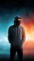 Mysterious figure in a hooded sweatshirt stands with headphones in a dramatic illuminated setting at night photo