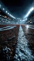 Nighttime view of an empty athletics track highlighting the starting line under stadium lights photo