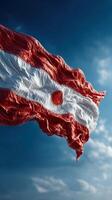 Waving flag featuring a circle against a bright blue sky with fluffy clouds on a sunny day photo