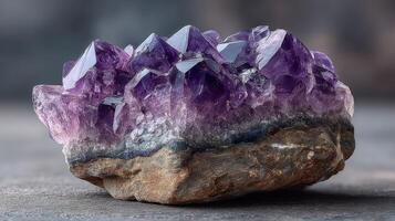 Beautiful amethyst crystal cluster reflecting light with stunning purple hues and natural rock base photo