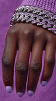 Close-up of a hand wearing a silver bracelet with pink stones against a vibrant purple background showcasing stylish accessories photo