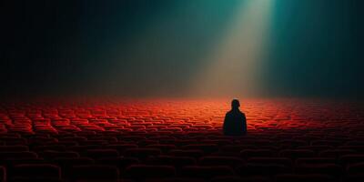 Lonely figure sits among empty theater seats in dim light during an evening performance photo