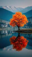 Vibrant autumn tree stands alone on the shore, reflecting in the calm lake with mountains in the background at dusk photo