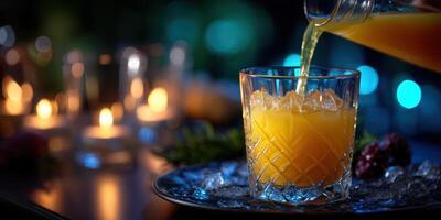 Refreshing orange drink poured over ice in an illuminated setting for a lively evening gathering photo