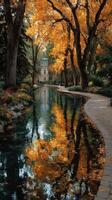 Autumn leaves reflect in calm water beside a winding path near a historic building in a serene park setting photo