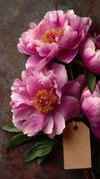 Beautiful pink peonies arranged elegantly with a blank tag on a textured surface for gift ideas or decoration photo