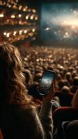 Audience member enjoying a performance while using a smartphone in a theater at night photo
