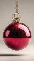 Shiny red Christmas ornament hanging elegantly against a neutral background during the festive season photo